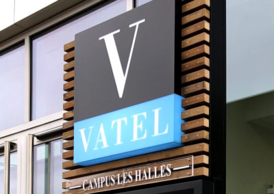 Vatel Campus des Halles - Bordeaux Conception et création totem caisson lumineux LED structure aluminium et bois intégration d'écran dans sa vitrine ouvrante l'atelier enseignes bordeaux